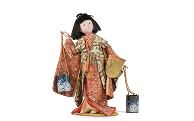JAPAN - 20th century Doll of a young woman standing, wearing a beige brown silk kimono decorated with flowers and carrying two seals. The eyes inlaid with glass. H. 44 cm.