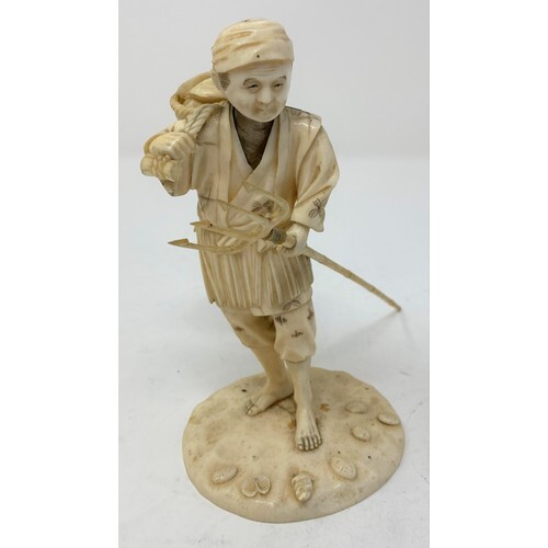 A Japanese carved ivory figure, of a shell fisherman, carryi...