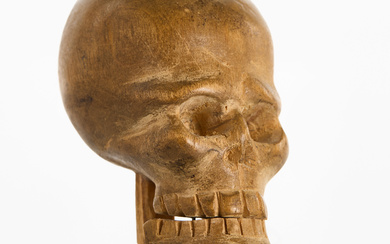 A WOODEN SCULPTURE, DÖSKULL, carved in birch, first half of the 20th century, on a wooden plinth.