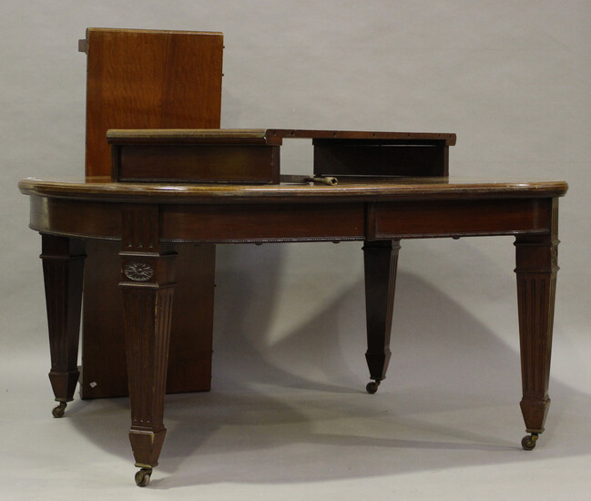 A large Edwardian mahogany extending dining table, the top with two extra leaves above a fluted frie