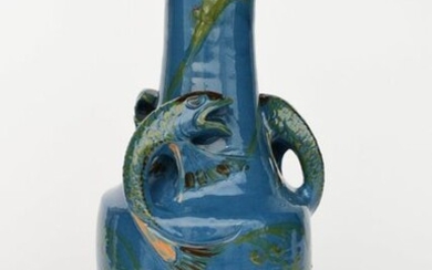 A tall C H Brannam pottery vase, shouldered form with tapering neck and everted rim, modelled in relief with three leaping scaly fish to the shoulder, the top rim pierced with waterweed sprays, in green, brown and ochre on a blue ground impressed...