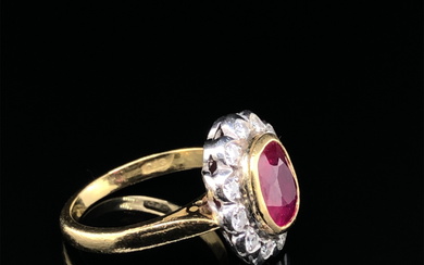 AN 18ct HALLMARKED GOLD RUBY AND DIAMOND OVAL SHAPED CLUSTER RING. THE SINGLE MEDIUM TO DARK