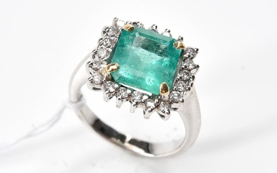 AN EMERALD AND DIAMOND CLUSTER RING-Centrally set with an emerald cut emerald weighing 3.10cts, surrounded by round brilliant cut di...