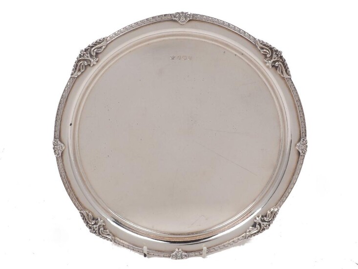 An Elizabeth II silver waiter, Sheffield, 1967, Alexander Clark & Co., of circular form with laurel border applied with foliate garland quarters to scroll spacers, the flat base raised on four foliate shouldered feet, 26.5cm dia., approx. weight 20oz