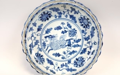 CHINE. PLAT en porcelaine bleu blanc à décor de daim, aile lobée à gouttière, idéogrammes...