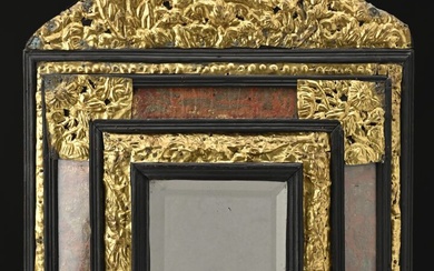 Miroir à fronton en bois noirci et décor de laiton doré travaillé au repoussé.Parecloses habillées...