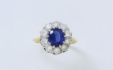 Partially rhodium-plated 750 thousandths gold ring set with a facetted oval sapphire surrounded by brilliant-cut diamonds.
