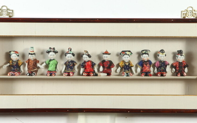 SET OF TEN JAPANESE POLYCHROMED PORCELAIN SEATED DOLLS IN DIORAMA...