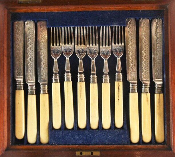Service à fruits comprenant 6 fourchettes et 6 couteaux, lame en argent étranger à décor de lambrequins, manche ivoire, présenté dans un coffret en acajou, 26 x 30 cm (avec clé). (AC).