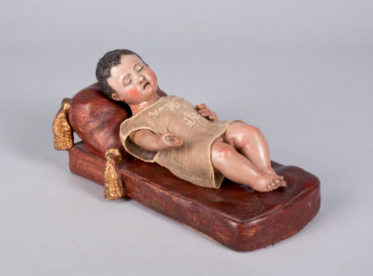 Sleeping child made of carved and polychrome wood. The cradle is made of polychrome and golden terracotta.