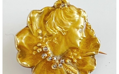 1900. BROCHE corolle en or jaune 750°/°° représentant une tête de femme ornée d’un collier...