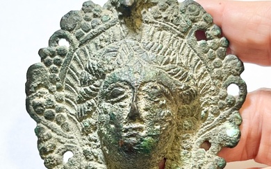 A BRONZE OIL LAMP HANDLE / REFLECTOR DEPICTING THE MASK...