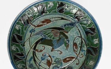 A C H Brannam Barnstaple pottery wall charger by Thomas Liberton, dated 1908, slip decorated with an exotic bird of paradise to the well, the rim with a band of stylised tulip stems, in brown, green and blue incised marks, 33.5cm. diam.