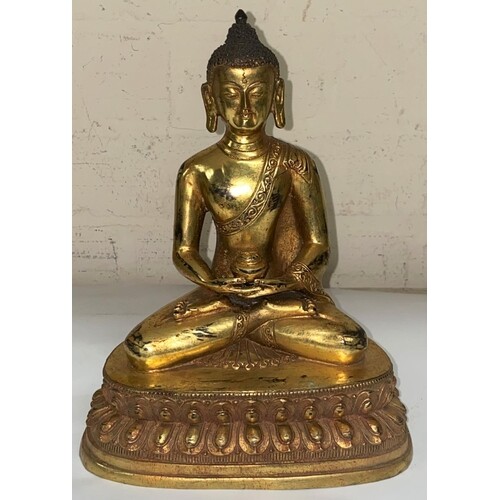 A Chinese bronze gilded figure of a buddha in lotus position...