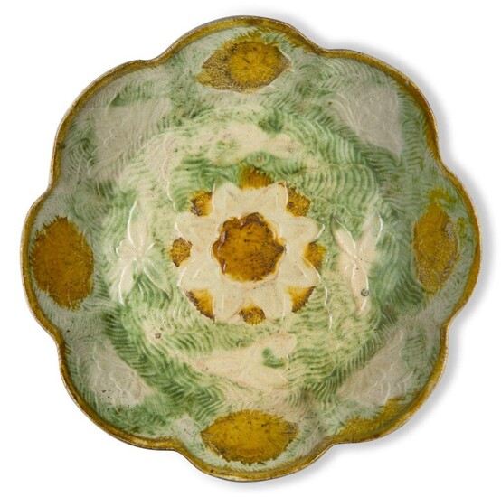 A Chinese pottery sancai-glazed foliate 'lotus' dish, Liao dynasty, moulded to the interior with a lotus flower decorated with splashes of amber and cream glaze, each lobe of the cavetto moulded with a lotus flower covered with alternating splashes...