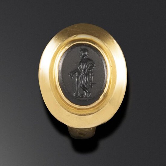A Roman onyx intaglio depicting Dionysus, c1st - 2nd century AD, Dionysus depicted leaning on a column and holding a kantharos, in a 19th century gold ring mount, intaglio 1.1cm high, ring size L