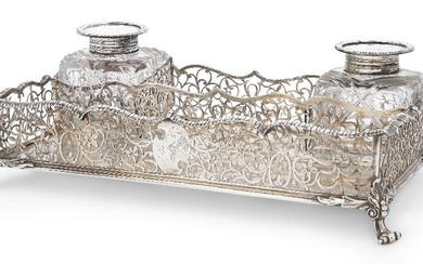 A Victorian silver gallery inkstand, London, 1896, Elkington & Co., of rectangular form, on four scroll and foliate feet, the sides pierced with scrolls and foliage to a shaped gadrooned rim, the silver mounted inkwells with hinged covers, same...