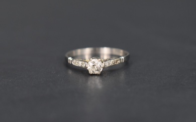 A diamond solitaire ring, approx 0.25ct in a raised claw set mount with diamond chip set shoulders