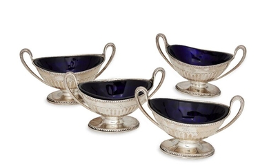 A set of four William IV silver salts, London, c.1835, maker JA, of oval form with reeded twin handles, the half-fluted bodies raised on a beaded oval foot, each engraved with lion crest to side and fitted with blue glass liner, 7.9cm high (to...