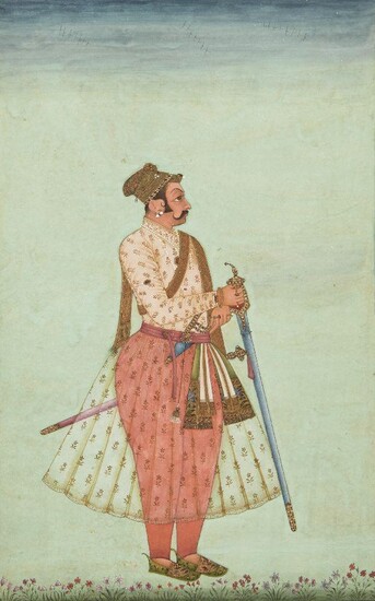 A standing portrait of Maharaja Shri Jaswant Singh Ji by Ka Murad, Bikaner, Rajasthan, North India, late 18th century, opaque pigments heightened with gold on paper, depicted on a green ground, and smelling a flower, his elegant clothes embroidered...
