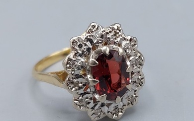 An 18ct gold cluster ring set with a central oval Garnet sur...