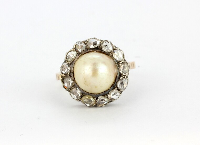 An antique yellow metal (tested minimum 9ct gold) ring set with a large pearl surrounded by rose cut diamonds, (O.5).