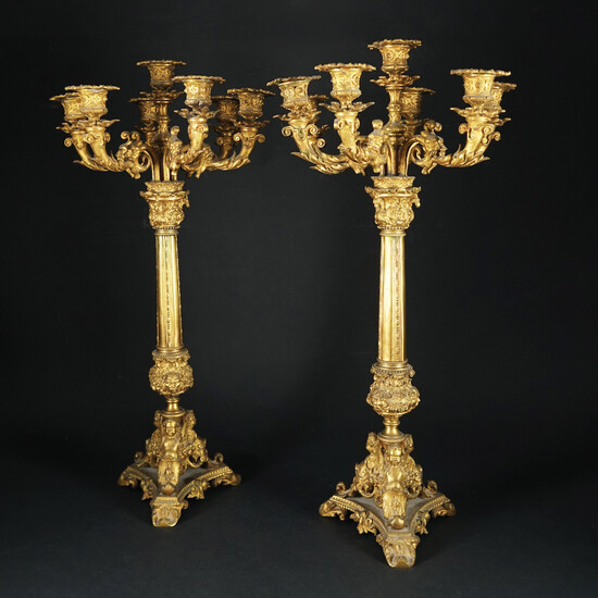 Coppia di candelabri a doppio uso in bronzo dorato a sette luci ciascuno....