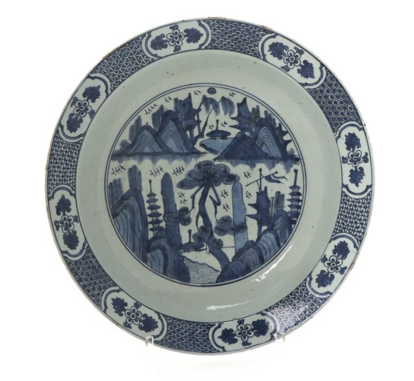 Large Chinese porcelain dish decorated in underglaze blue with scenery, border divided into fields with cartouches. 19th-20th century. Diam. 41,5 cm.