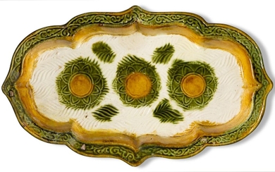 A Chinese pottery sancai-glazed quatrefoil dish, Liao dynasty, the interior moulded with three flowerheads in amber and green glaze on a cream-coloured ground impressed with wave patterns and splashed with green, the cavetto amber-glazed and the...