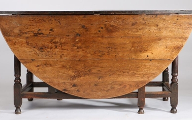 A large 18th Century oak gateleg table, the oval drop leaf table above a shallow frieze, one end