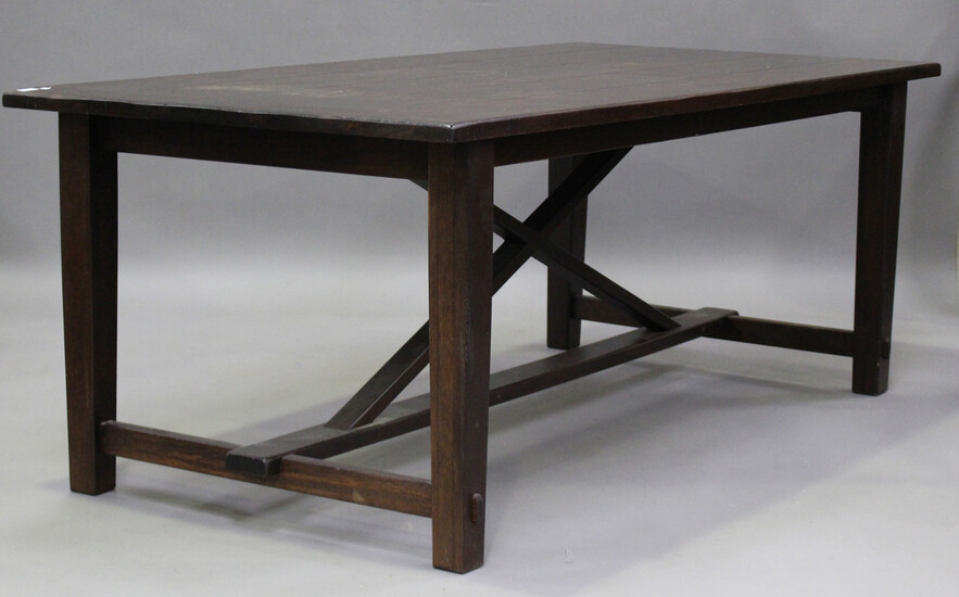 A modern hardwood rectangular dining table, raised on block legs united by an 'X'-frame su