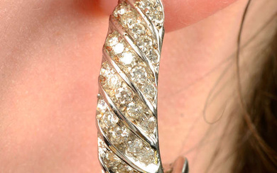 A pair of brilliant-cut diamond spiral half hoop earrings.