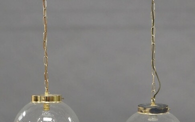 A pair of pendant ceiling lights, late 20th century, each with clear and bubbled spherical glass diffusers, suspended on plated chains, each 80cm high (2) It is the buyer's responsibility to ensure that electrical items are professionally rewired...
