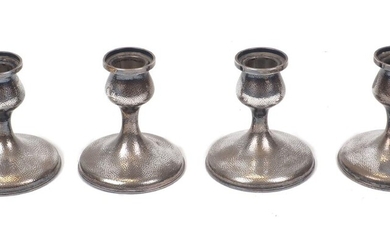 A set of four Japanese candlesticks, stamped pure silver, Yamato Bros, Kobe, of hammered design, each capital raised on a spreading circular foot, 7.7cm high, bases filled (4)