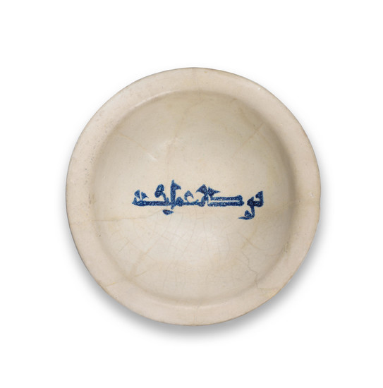 A signed Abbasid slip-painted calligraphic pottery bowl, Mesopotamia, 9th Century