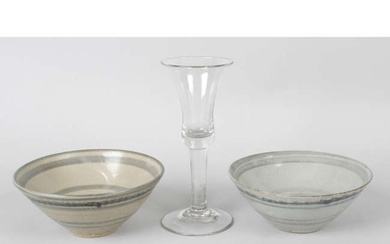 A wine glass and two Chinese pottery bowls.