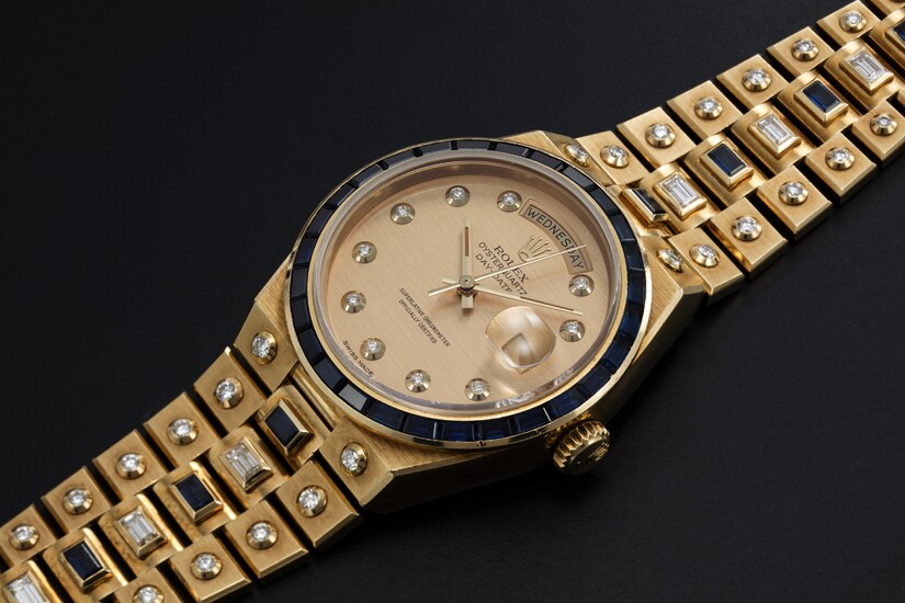 ROLEX "MECCANO" REF. 19168, A GOLD DAY-DATE OYSTERQUARTZ SET WITH DIAMONDS AND SAPPHIRES