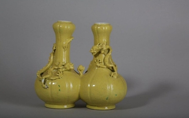 A CHINESE YELLOW-GLAZED DOUBLE 'DRAGON' VASE. Qing Dynasty. The lobed bodies with cylindrical necks terminating in a garlic mouth rims joined by the side and moulded with two sinuous dragons contesting a sacred pearl, all decorated with a bright...