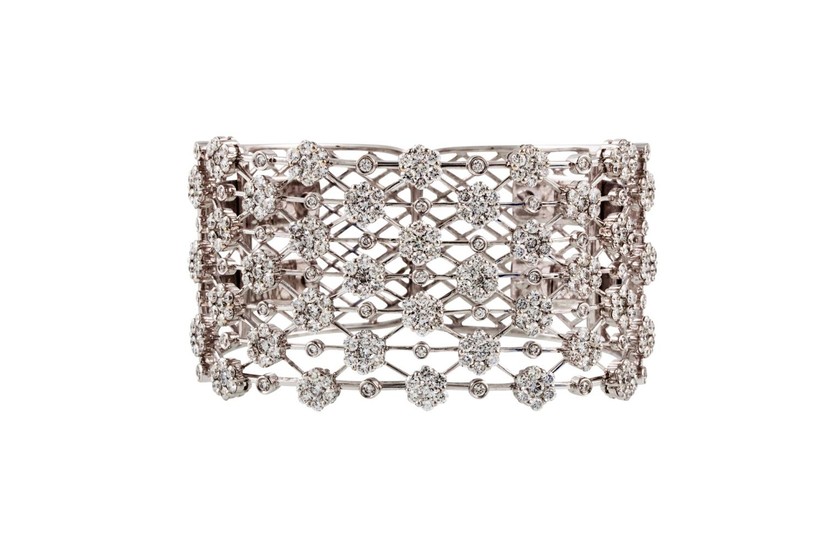 A DIAMOND SET CUFF BANGLE, set with daisy clusters of approx...