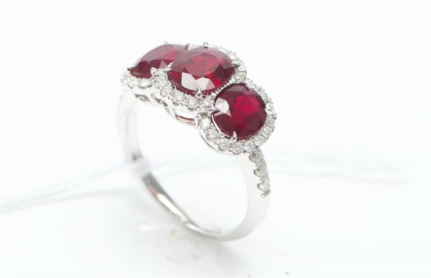 A THREE STONE RUBY AND DIAMOND DRESS RING IN 18CT WHITE GOLD, THE RUBIES TOTALLING 3.69CTS AND DIAMONDS ESTIMATED 0.50CT, SIZE M, 4....