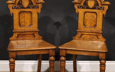 A pair of Victorian oak hall chairs, each shaped back with m...