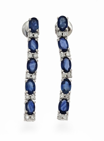 SOLD. A pair of ear pendants each set with five oval-cut sapphires flanked by numerous...