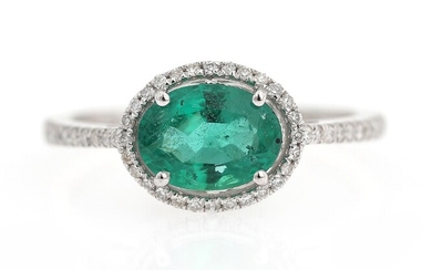 SOLD. An emerald and diamond ring set with an emerald weighing app. 0.97 ct. encircled...