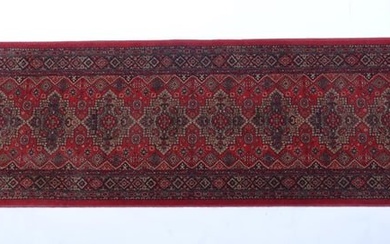 Carpet / Rug : A red ground runner with repeating motifs to centre, bordered by geometric banding.