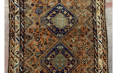 Tappeto Shiraz, Persia, inizio secolo XX. Decoro con due medaglioni romboidali blu su fondo mattone (Difetti, rapature, mancanze)(cm 192x166)