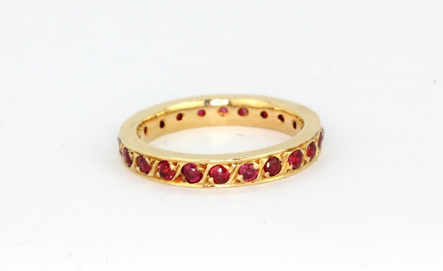 A 14ct yellow gold (worn stamp 585) ruby set full eternity ring, (K).