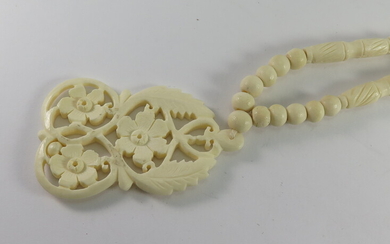 A CARVED BONE PENDANT AND BEAD NECKLACE