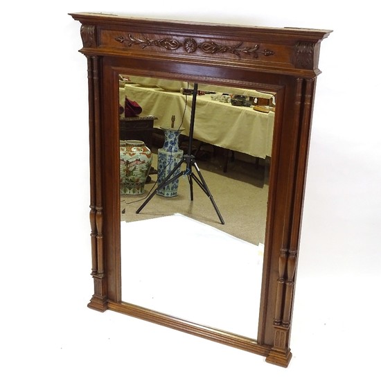 A French carved walnut-framed wall mirror, with fluted twin ...