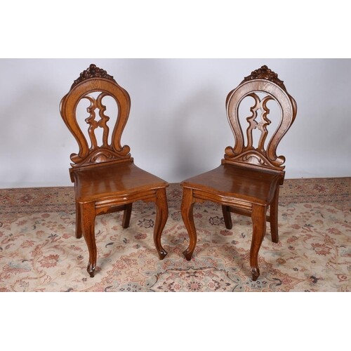 A PAIR OF VICTORIAN OAK HALL CHAIRS the pierced carved back ...
