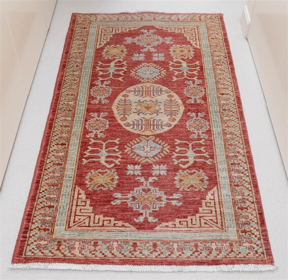 A mid-size woollen carpet with stylized geometric design, a central...